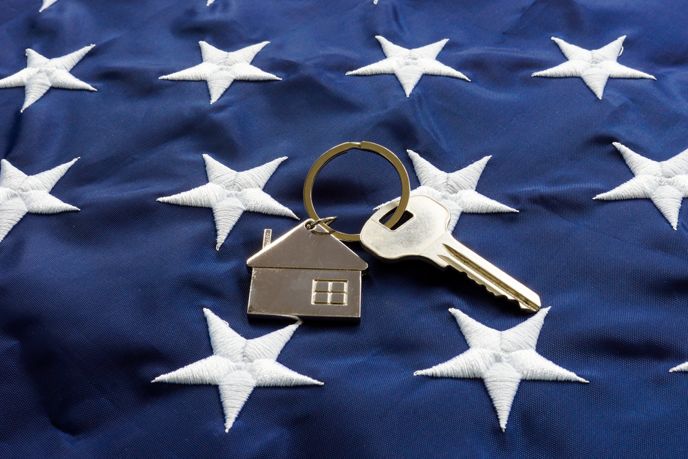 va loan | key with house keychain laid on United States Flag