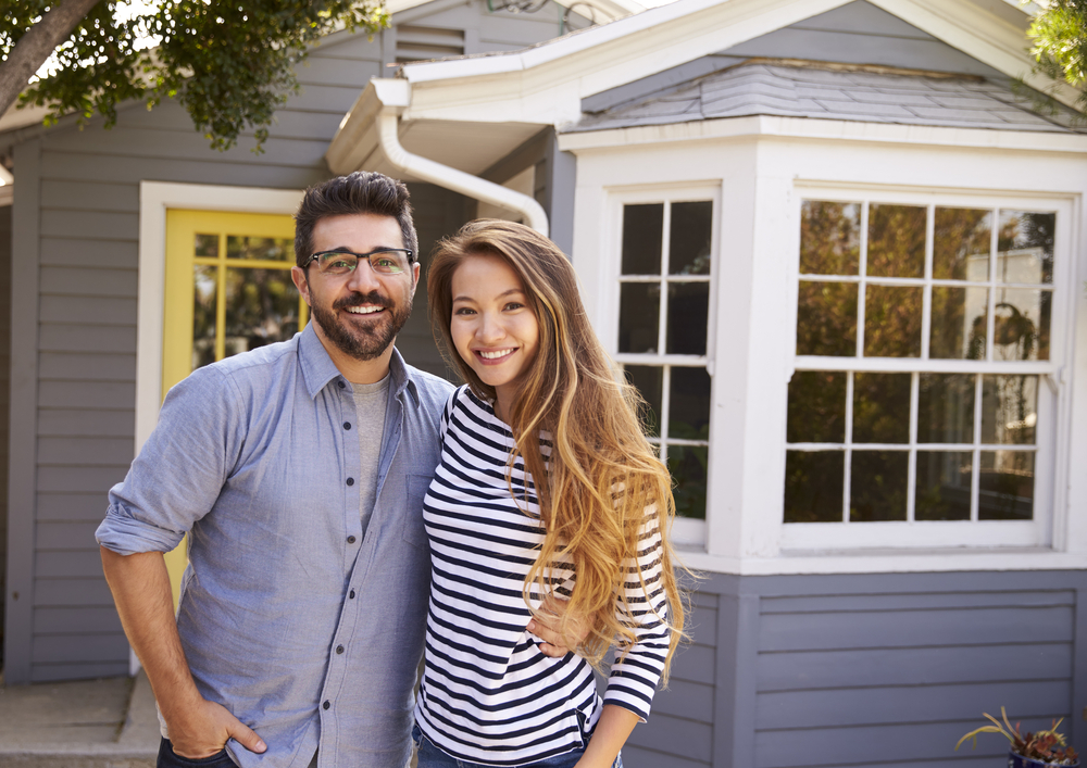 buying a home with low income | couple standing in front of house.